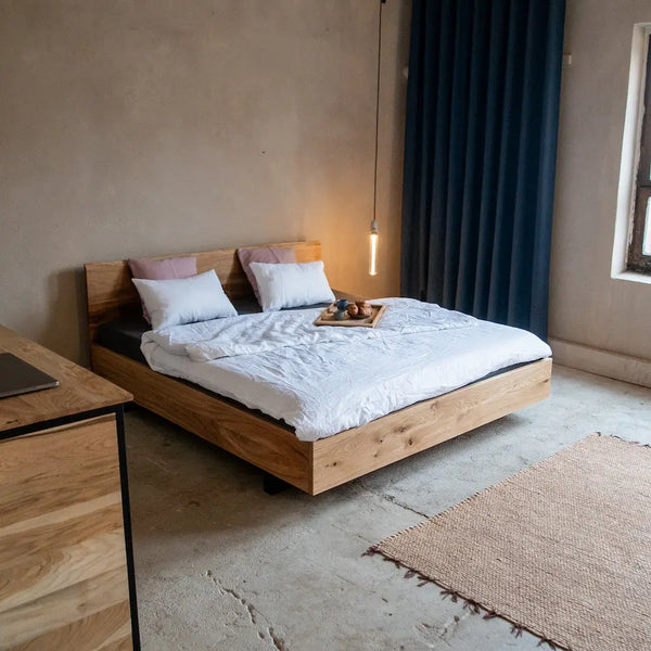 Massivholzbett Eiche mit Metallfüßen, minimalistisches Schlafzimmer mit Kommode, Teppich & Hängeleuchte.