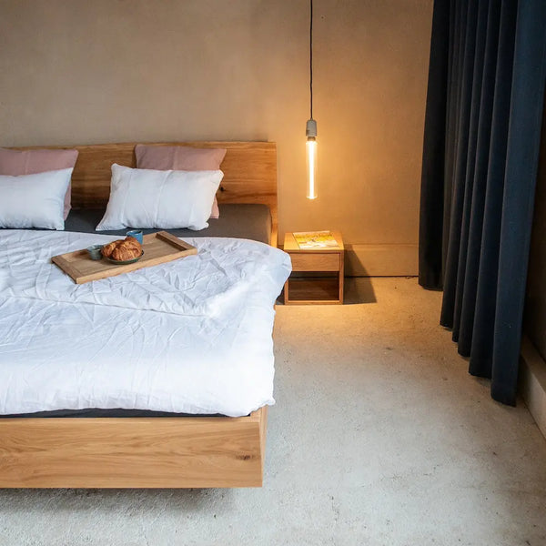 Massivholzbett aus Eiche mit Kufengestell, weißer Bettwäsche, Serviertablett, Industrial-Schlafzimmer.