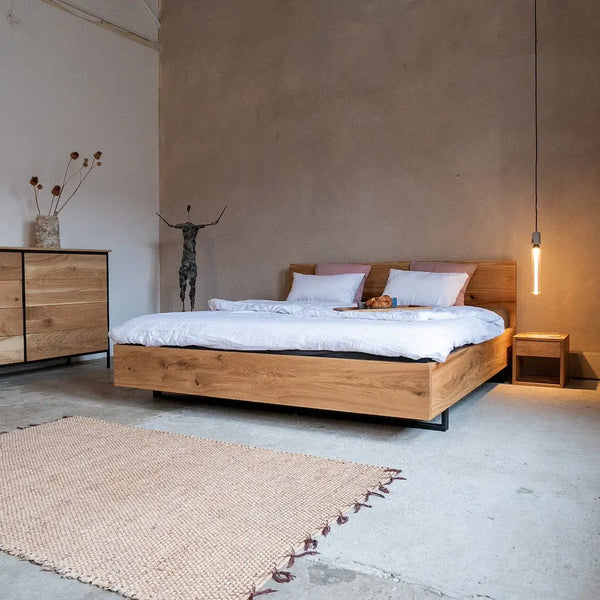 Massivholzbett mit Kufengestell aus Eiche, Industrial-Stil, weiße Bettwäsche, rustikale Loft-Ästhetik.