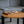 Minimalistisches Serviertablett aus Eiche auf Holztisch. Darauf ein Teller mit Brot und ein Holzbrett mit Butter. Graues Sofa im Hintergrund.